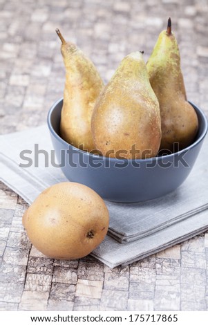 Fresh pears in a bowl on a table on linen napkin