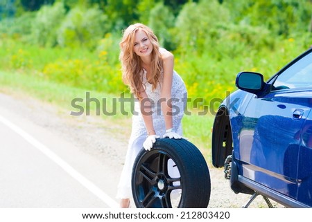 beautiful blond woman near car and wheel tire