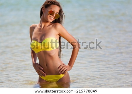 beautiful fun and joy brunette woman in yellow bikini posing  tropical  blue sea water has sports and tan body