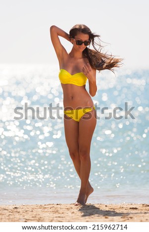 beautiful fun and joy brunette woman in yellow bikini posing  tropical  blue sea water has sports and tan body