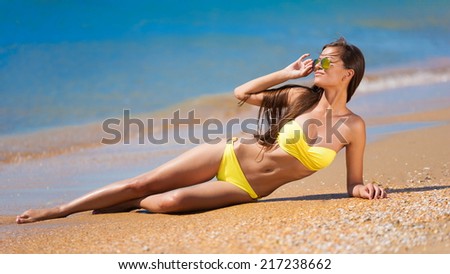 beautiful fun and joy brunette woman in yellow bikini posing tropical blue sea water has sports and tan body