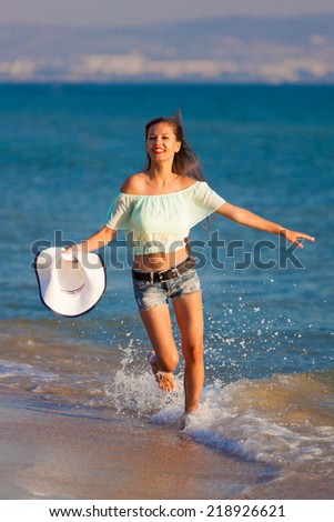 beautiful fun and joy brunette woman in jeans shorts run  blue sea water has sports and tan body