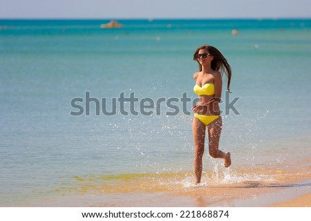 beautiful fun and joy brunette woman in yellow bikini run tropical  blue sea water has sports and tan body