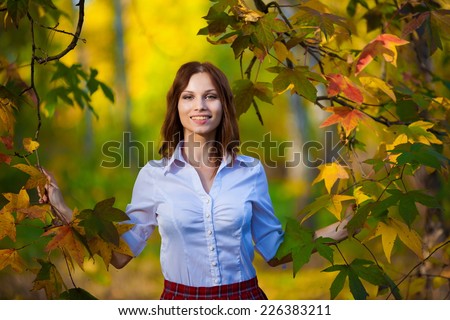 beautiful  smiling  woman in red skirt and white blouse  posing in autumn nature