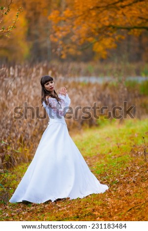 beautiful and happy smiling  brunette bride in white lacy satin dress european style  autumn background
