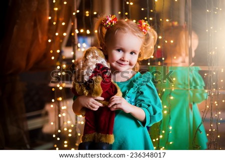 beautiful  smiling  little blonde girl  with  soft toy on christmas  lights background birthday