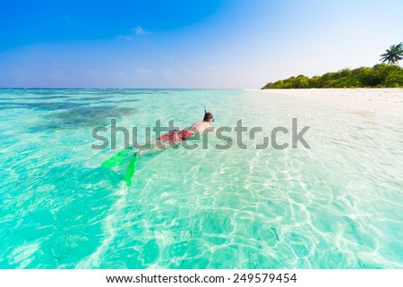man  with flippers, mask and tube snorkeling in Maldives  romantic  atoll island paradise luxury  resort about coral reef