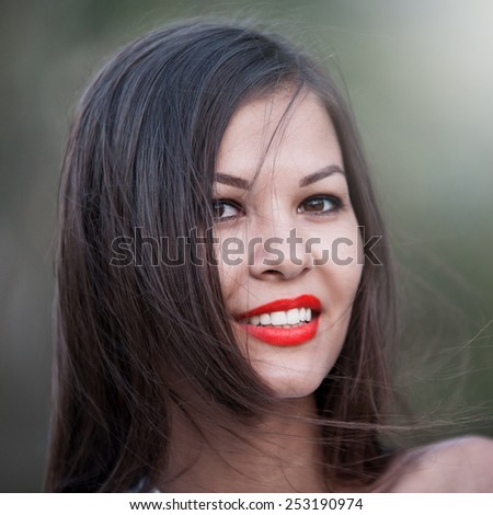 beautiful fun and joy brunette woman in green background has red smiling lips