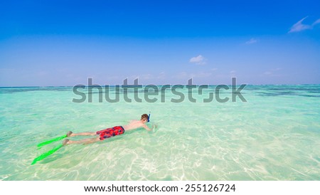 man  with flippers, mask and tube snorkeling in romantic  atoll island paradise luxury  resort about coral reef