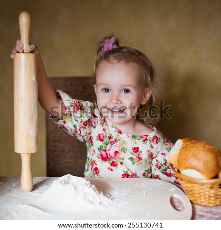 beautiful  fun smiling  little blonde girl  with rolling pin cook french bread