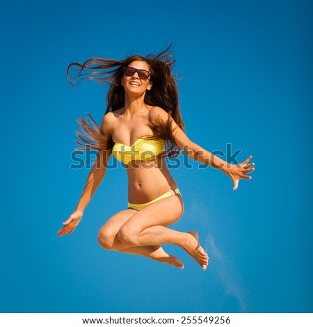 beautiful fun and joy brunette smiling woman in yellow bikini jump  blue sky  has sports and tan body