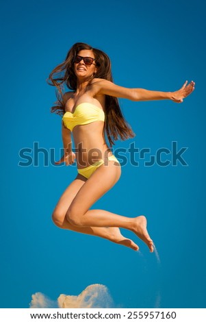 beautiful fun and joy brunette smiling lady woman in yellow bikini jump  blue sky  has sports and tan body
