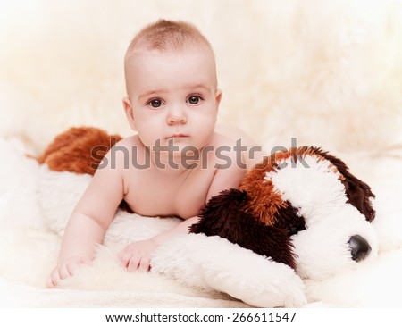 beautiful baby boy with brown eyes lying and soft toy dog kids background, shallow depth of field