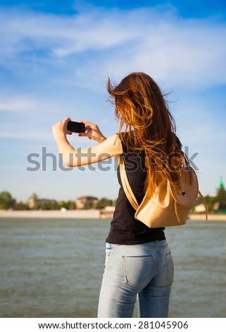 beautiful sensuality elegance lady haired woman happy fun back black t-shirt jeans urban city portrait nature slim body river blue sky river water space impressions smart phone cellphone taking photo