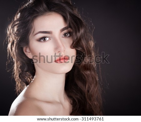 Beautiful sensuality elegance lady brunette face woman, has brown eyes, curly gloss hair, sexy lips. Studio portrait.  Nature romantic pure makeup. Black background. Beauty hairstyle.
