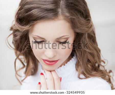 Beautiful young romantic elegant woman face, has closed eyes, haired nature hair, long eyelashes, hand with red manicure, sexy lips. Pure makeup. White blouse.