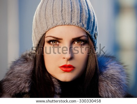 Beautiful sensuality elegance brunette woman, has happy fun cheerful smiling face, brown eyes, fur coat and gray knitted hat, sexy lips. Portrait nature. Sunny day.