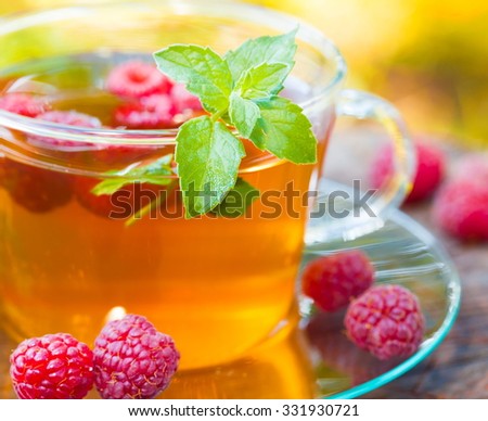 Beautiful green tea with raspberries and mint. Garden fruit background. Sunny day. Lifestyle medicine.
