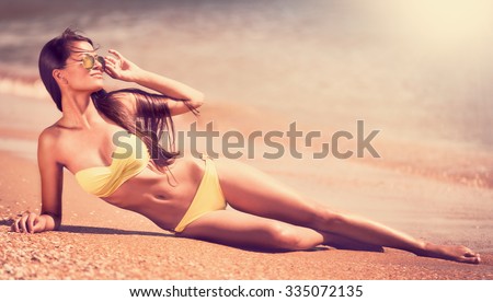 Portrait sexy beautiful brunette woman, has yellow bikini,  sunglasses, slim tan body, fun face. Posing in tropical hot sea. Luxury resort. Travel lifestyle. Nature background. Sunny day.