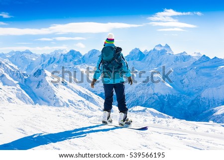 Beautiful amazing day winter mountains. A woman rides snowboard. Sport hike in holidays. Landscape inspiring. Cool fun girl. Blue sky and white snow. Happy hobby, blue jacket