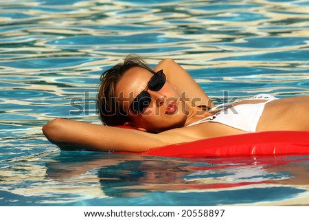 Woman swimming On An Air Mattress In Blue Pool