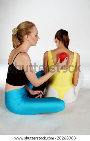 A Girl massaging another girl with a red spike ball