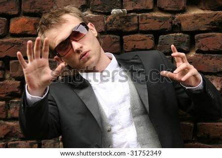 fashion man in sunglasses at the brick wall