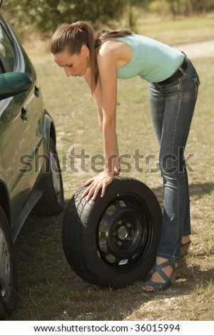 A woman changing a tire on a car outdoor