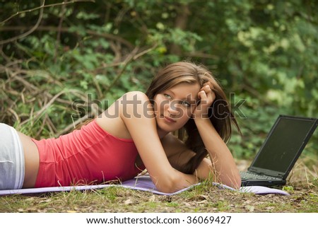 young woman with laptop relaxing in a natural outdoor setting