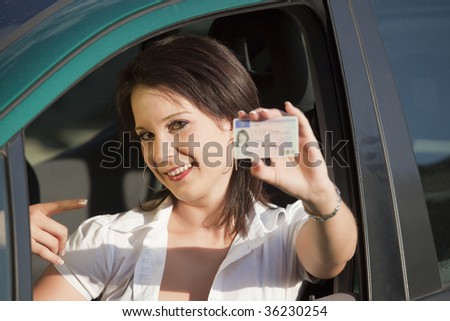 young female showing her driving license into the camera