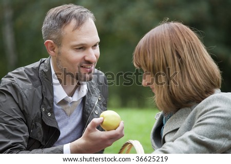romantic couple by picnic, man gives a apple to woman