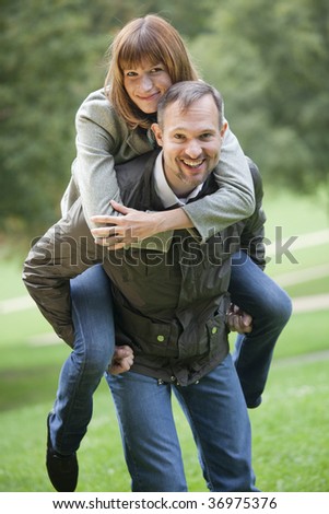 happy couple in a city park, man carrying woman on his back