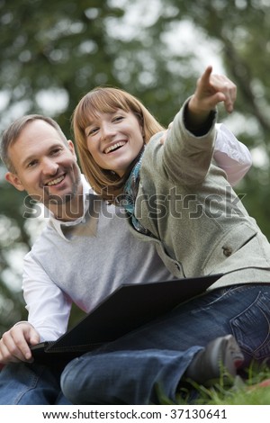 romantic couple with photo album, woman points with finger on something