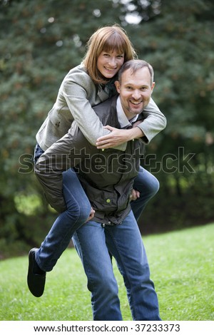 romantic couple in a city park, man carrying woman on his back