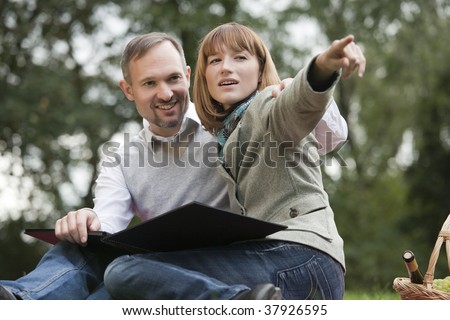 romantic couple in park, woman points with finger on something