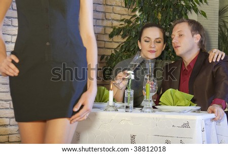 man looking at a nice girl passing by while dining out with his girlfriend in restaurant