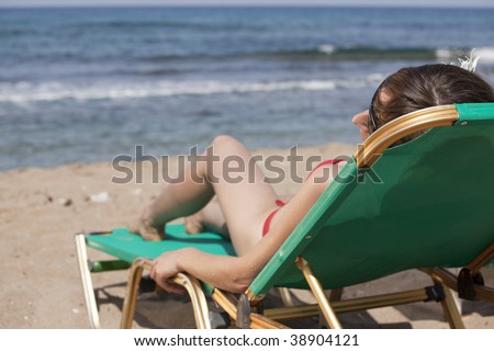 Young woman sunbathing on the chair near the ocean