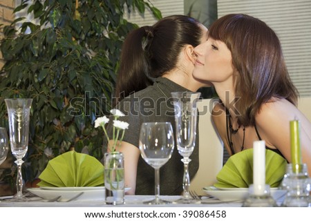 two female friends kissing each other by meeting in restaurant