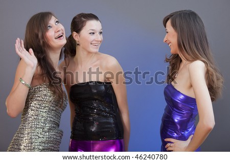 three women in party dresses talking over grey background