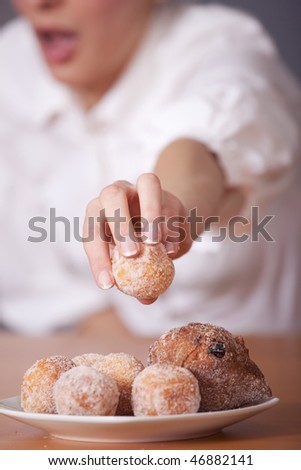 surprised woman reaches for sugar cake over grey background