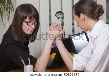 Business arm wrestling between two young women in a office