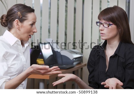 two business women gossip in a office
