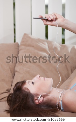 woman lying on the sofa and hearing music in earphones