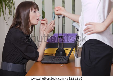 female secretary putting on lip gloss in the office