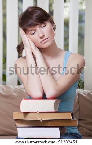 female student with pile of books takes a break and sleeps, sitting on sofa