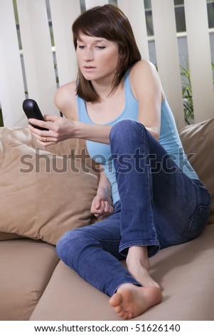 woman sitting on the sofa and holding phone in her hand