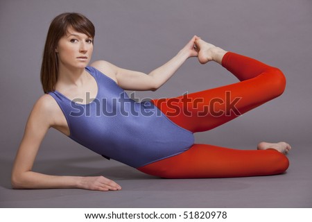 young woman in leotard doing gymnastic exercises on the ground