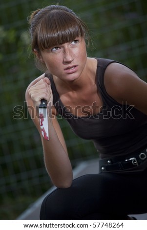 angry woman with bloody knife in her hand outdoor