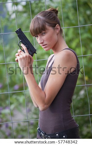 young female agent with a gun outdoors