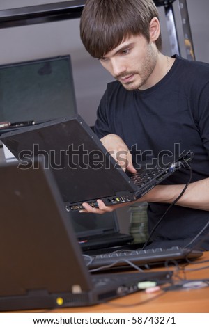 male computer technician installing new software on laptop